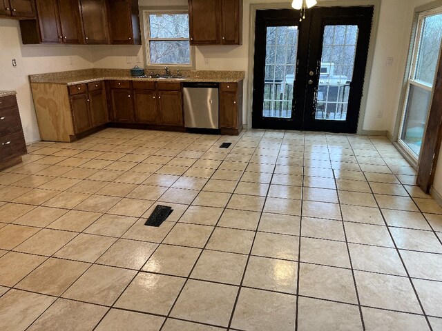 kitchen with light stone counters, light tile patterned flooring, a sink, french doors, and stainless steel dishwasher