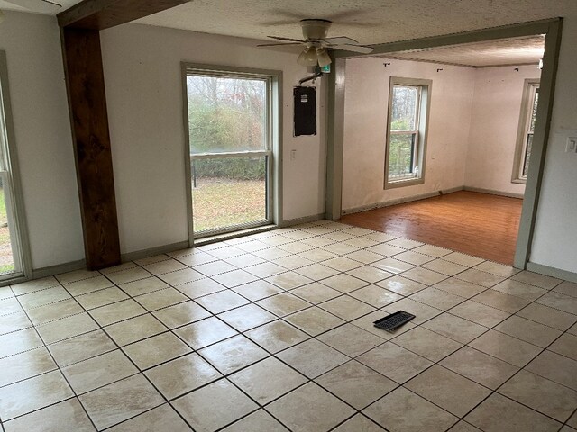 spare room featuring ceiling fan, baseboards, a textured ceiling, and light tile patterned flooring