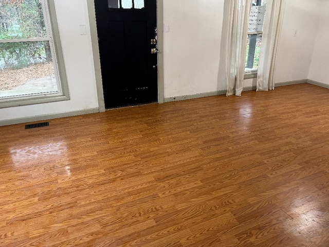 spare room featuring baseboards, wood finished floors, visible vents, and a healthy amount of sunlight