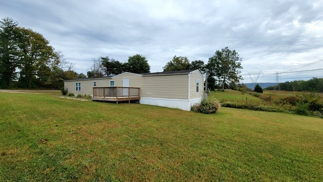 rear view of house featuring a yard and a wooden deck