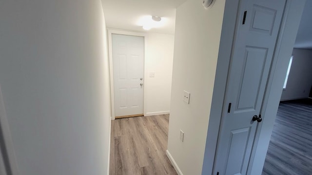 corridor featuring baseboards and light wood finished floors