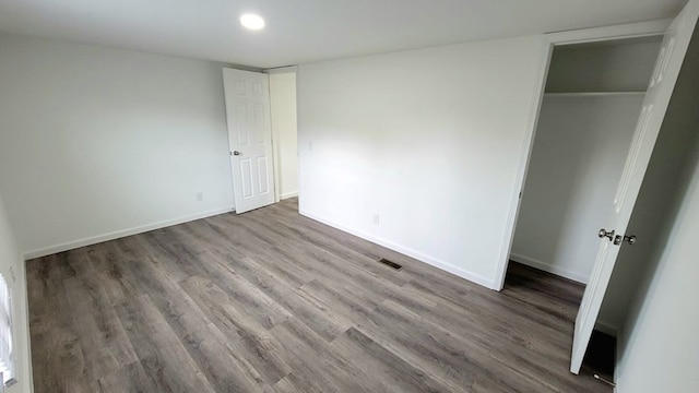 unfurnished bedroom featuring a closet, wood finished floors, visible vents, and baseboards