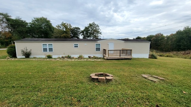 back of house with an outdoor fire pit, a yard, and a wooden deck