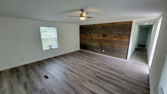 unfurnished room with ceiling fan, wood finished floors, visible vents, baseboards, and vaulted ceiling