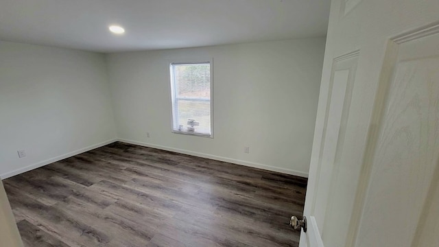 spare room with baseboards and wood finished floors