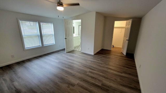 unfurnished bedroom featuring ensuite bathroom, dark wood finished floors, and baseboards