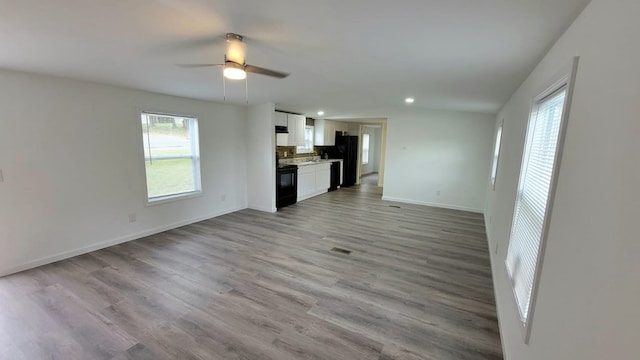 unfurnished living room with baseboards, a ceiling fan, light wood-style flooring, a sink, and recessed lighting