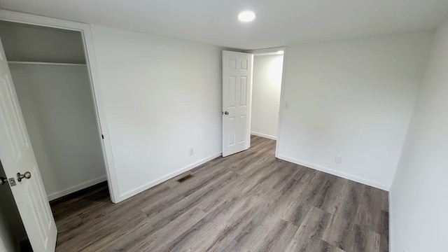 unfurnished bedroom with baseboards, a closet, visible vents, and light wood-style floors