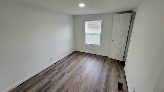 unfurnished bedroom with dark wood-style floors, visible vents, and baseboards