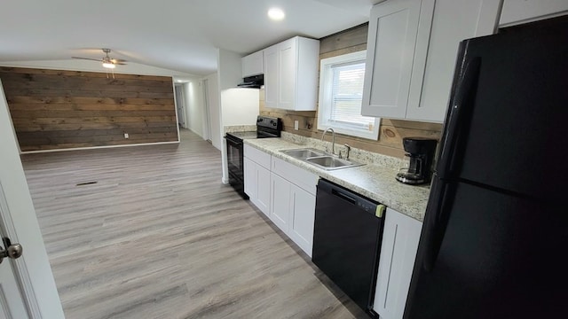 kitchen with light wood finished floors, white cabinets, under cabinet range hood, black appliances, and a sink