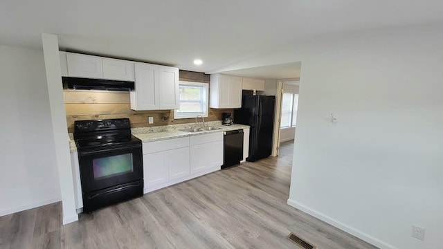 kitchen with visible vents, under cabinet range hood, black appliances, white cabinetry, and a sink