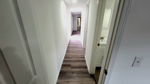 corridor featuring baseboards and wood finished floors