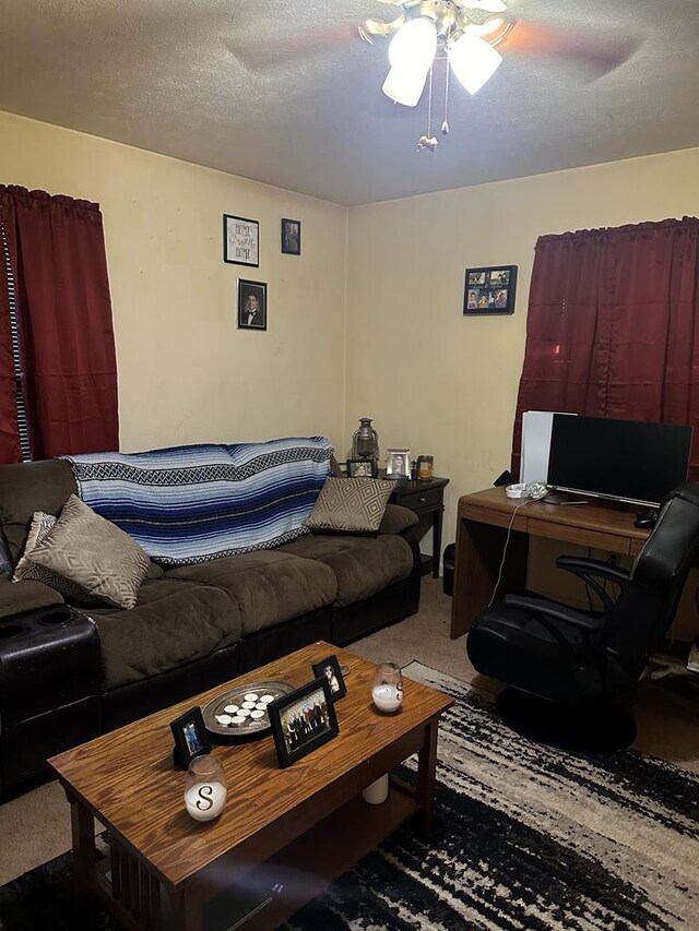 living room featuring a ceiling fan, carpet flooring, and a textured ceiling