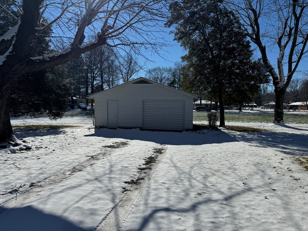 snow covered structure with an outbuilding