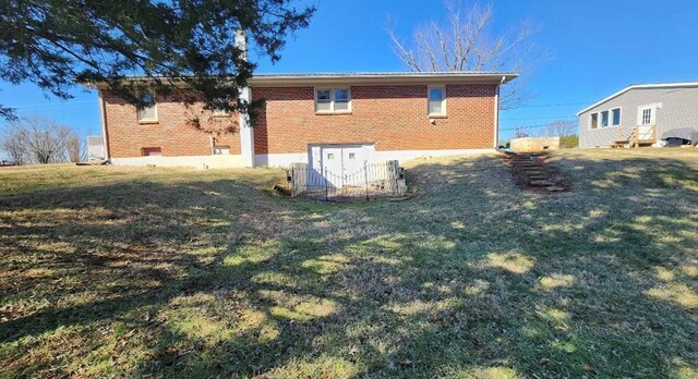 rear view of house featuring brick siding and a lawn