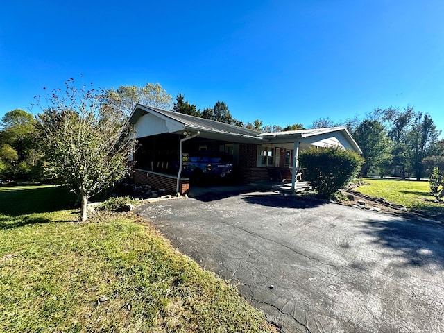 view of home's exterior with metal roof, aphalt driveway, an attached carport, a yard, and brick siding