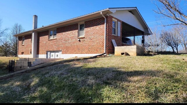 view of home's exterior with brick siding, a lawn, and a chimney