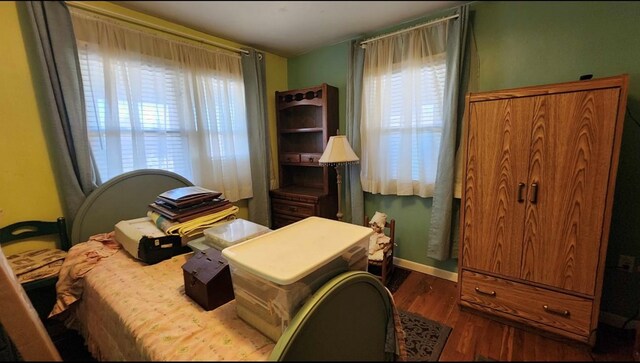 bedroom with dark wood-type flooring and baseboards