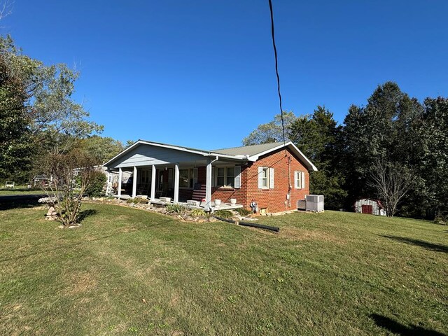 back of house with a yard, a porch, cooling unit, and brick siding