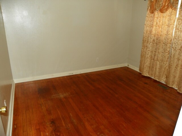 unfurnished room featuring baseboards and wood finished floors