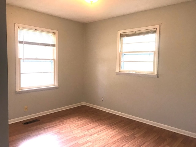 unfurnished room with baseboards, visible vents, and wood finished floors