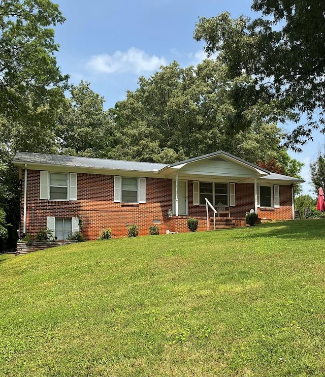 ranch-style home with brick siding, covered porch, and a front yard