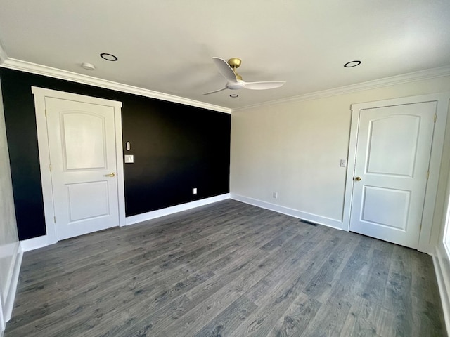 spare room with a ceiling fan, dark wood-style flooring, crown molding, and baseboards