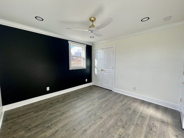 spare room featuring baseboards, ceiling fan, dark wood-style flooring, and crown molding