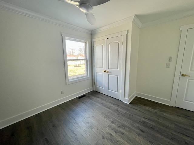 unfurnished bedroom featuring dark wood-style floors, a closet, crown molding, and baseboards