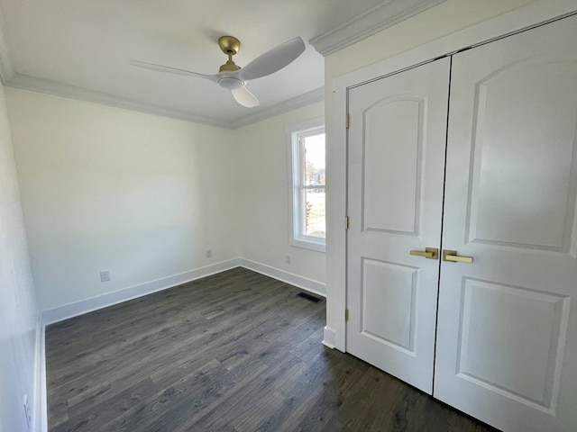 unfurnished bedroom featuring dark wood finished floors, a closet, visible vents, ornamental molding, and baseboards