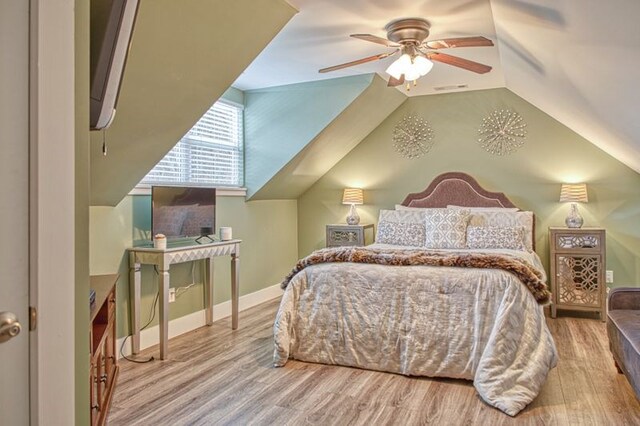 bedroom with vaulted ceiling, wood finished floors, visible vents, and baseboards