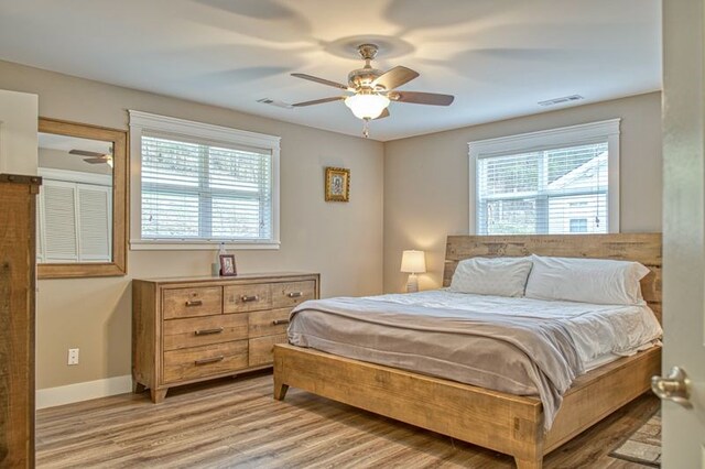 bedroom featuring light wood finished floors, multiple windows, visible vents, and baseboards