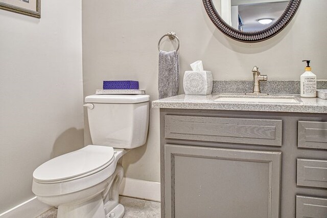 half bath featuring vanity, toilet, and tile patterned floors