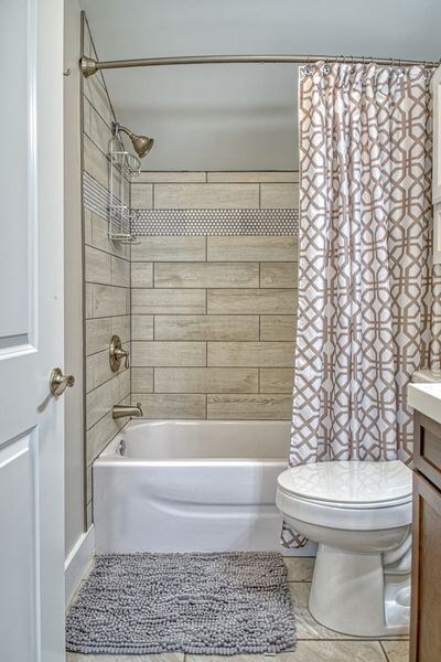 bathroom featuring shower / bath combination with curtain, vanity, toilet, and tile patterned floors