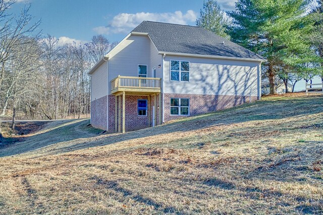 back of house with brick siding and a lawn