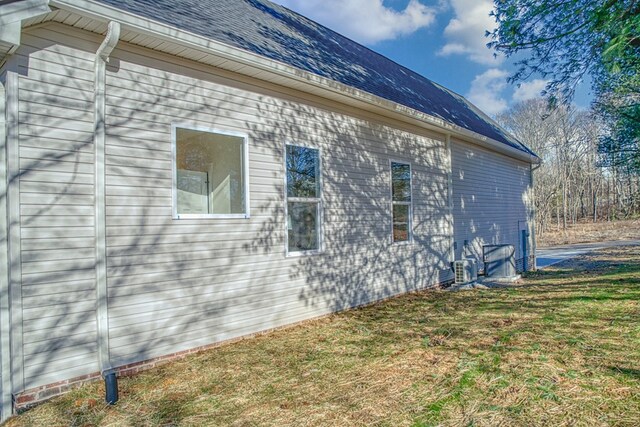 view of side of home featuring a lawn and roof with shingles