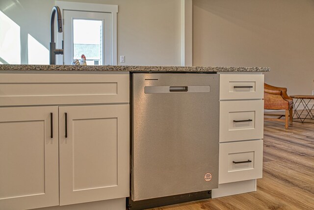 details featuring light stone counters, white cabinetry, dishwasher, and light wood finished floors