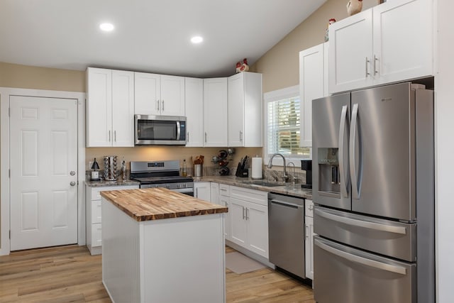 kitchen with appliances with stainless steel finishes, a center island, white cabinetry, and a sink