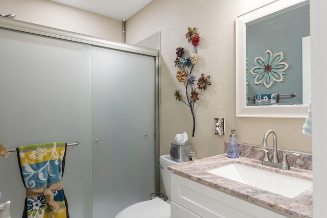 full bath with toilet, a textured wall, a stall shower, and vanity