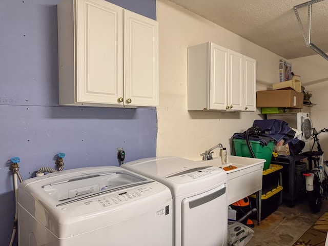 laundry room featuring cabinet space, a sink, washer and clothes dryer, and a textured ceiling