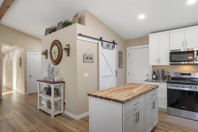 kitchen featuring stainless steel appliances, butcher block counters, white cabinetry, and a barn door