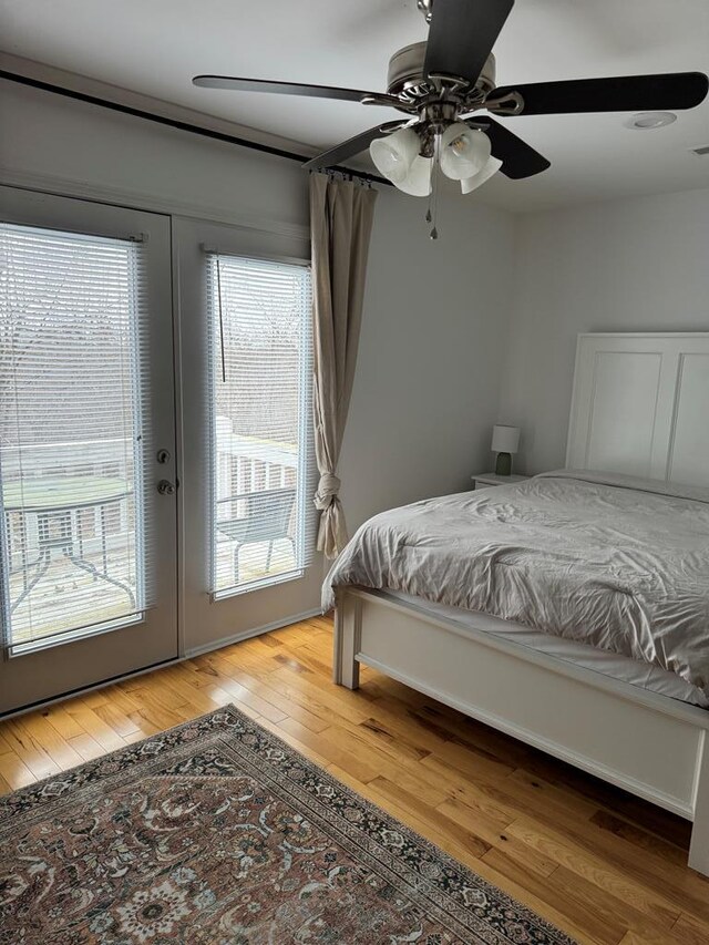 bedroom with ceiling fan, access to outside, wood finished floors, and french doors