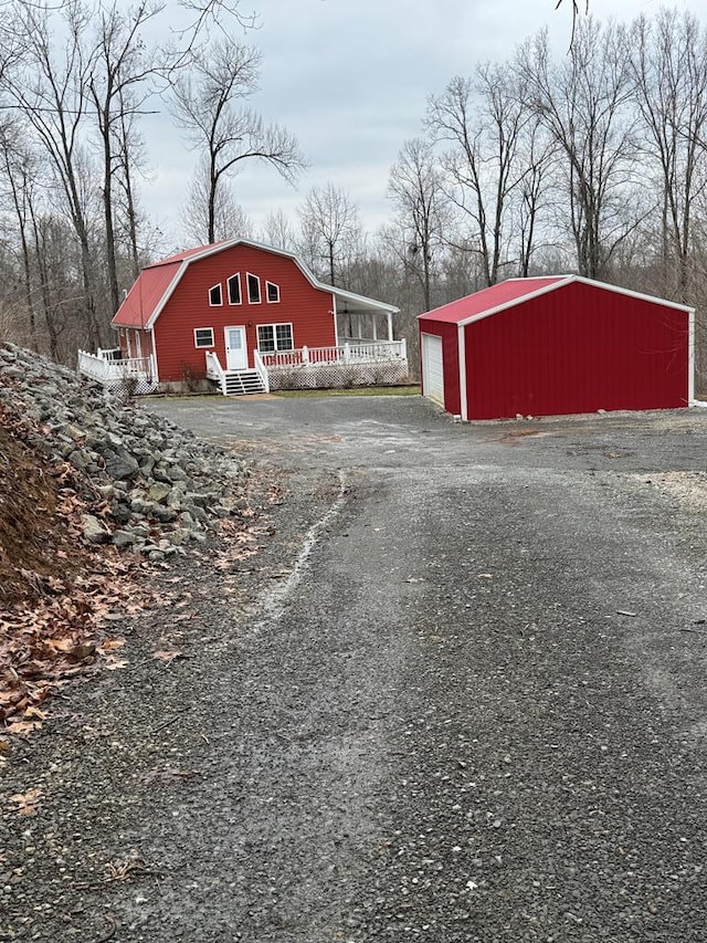 view of outbuilding with a garage, an outdoor structure, and driveway