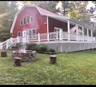 rear view of house featuring an outdoor fire pit, a deck, a lawn, and a gambrel roof