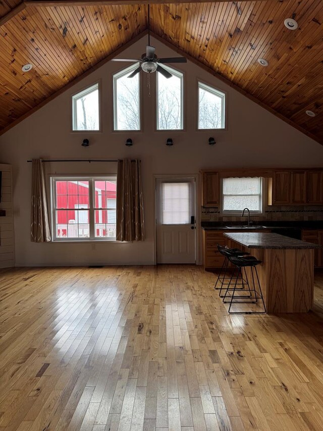 unfurnished living room featuring light wood-type flooring, wood ceiling, high vaulted ceiling, and a sink