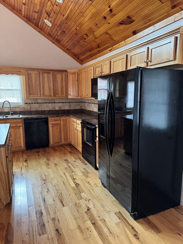 kitchen featuring dark countertops, wood ceiling, vaulted ceiling, black appliances, and a sink