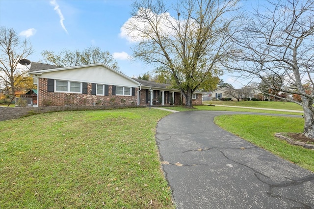 ranch-style house with driveway, brick siding, and a front lawn