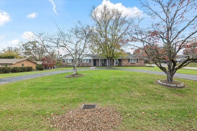 single story home with driveway, brick siding, and a front yard