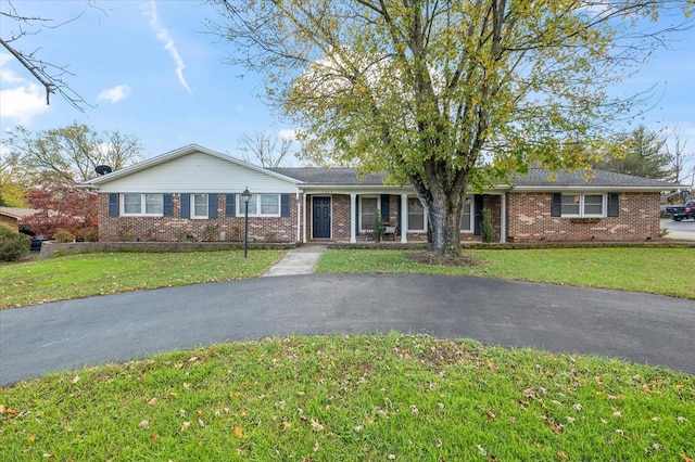 single story home featuring brick siding, aphalt driveway, and a front yard