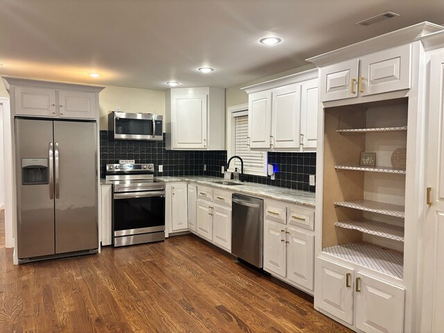 kitchen with dark wood-style flooring, stainless steel appliances, visible vents, white cabinets, and a sink